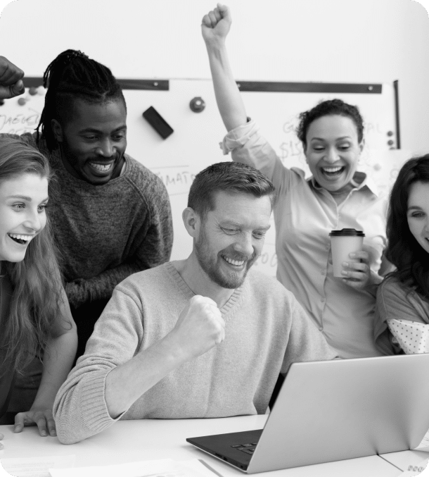 A group of five diverse colleagues celebrates a success at a meeting, showing expressions of joy and accomplishment around a laptop.